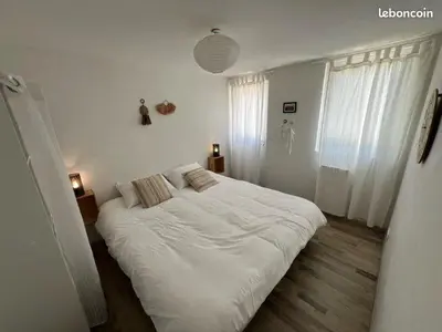 a white bedroom with a large bed with white sheets at appartement avec piscine in Gargas