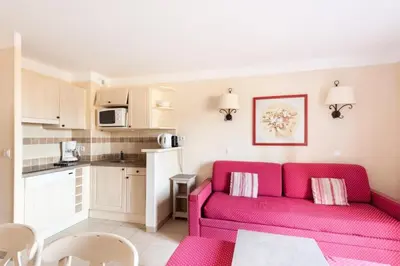 a living room with a red couch and a kitchen at Les Coteaux de Pont Royal en Provence - maeva Home - Maison 3 pièces 6 personnes - Sélection MAE-9993 in Mallemort