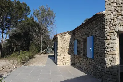 a stone building with blue windows and a sidewalk at Mas provençal - Beautiful Provencal farmhouse, heated pool in Murs