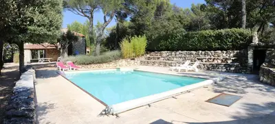 a swimming pool with two chairs and a stone wall at Mas provençal - Beautiful Provencal farmhouse, heated pool in Murs