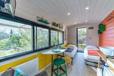 a tiny house with a table and a couch at La roulotte de Valou in Noves