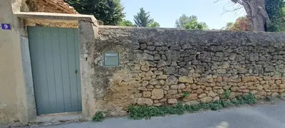 a stone wall with a green door and a stone wall at Location Le Tilleul in Pélissanne