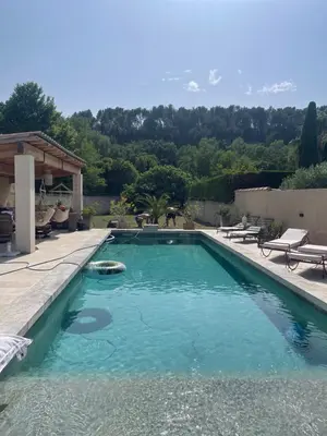 a swimming pool with blue water in a backyard at Belle bastide provençale in Noves