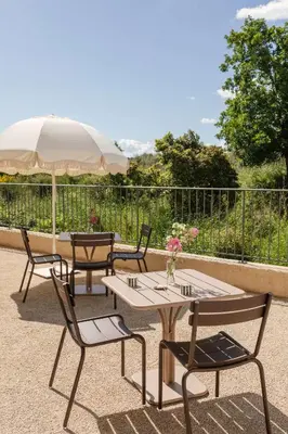 a group of tables and chairs with an umbrella at Mas de l'Etoile in Aureille
