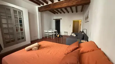a bedroom with an orange bed and a living room at Studio dans le centre ancien in Carpentras