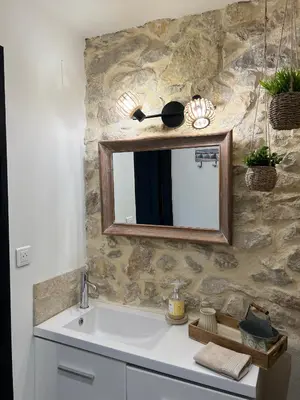 a bathroom with a sink and a mirror on a stone wall at L'Ecrin de Mérindol in Mérindol