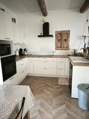 a kitchen with white cabinets and a wooden floor at La dominique in Villes-sur-Auzon