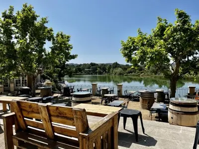 a view of a lake with tables and chairs and a bench at Maison en Provence avec Piscine et Climatisation - FR-1-658-36 in Mallemort