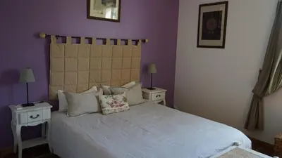 a bedroom with a white bed with purple walls at Bastide Clementine in LʼIsle-sur-la-Sorgue