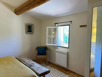 a bedroom with a bed and a window and a chair at Provençal Villa With Luberon Views in Céreste