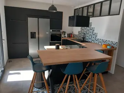 a kitchen with a wooden table and blue bar stools at Maison en Provence 7 personnes avec piscine in Carpentras