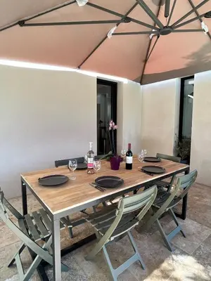 a wooden table with chairs and wine bottles on it at Maison en Provence 7 personnes avec piscine in Carpentras