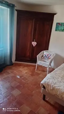 a room with a bed and a chair and a cabinet at Chez Rachel in La Bastide-des-Jourdans