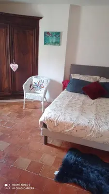 a bedroom with a bed and a chair at Chez Rachel in La Bastide-des-Jourdans