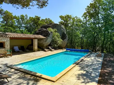 a swimming pool in front of a house with a rock at Mas à Gordes avec piscine et vue incroyable à 900m du village in Gordes