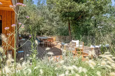 a patio with a table and chairs in a yard at Cabane dIsmou Pool & Wood Design in La Roque-dʼAnthéron