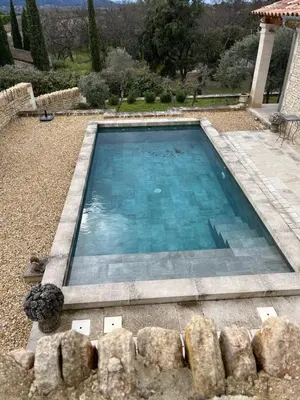 a swimming pool with blue water in a yard at Maison dans un hameau avec piscine in Gordes