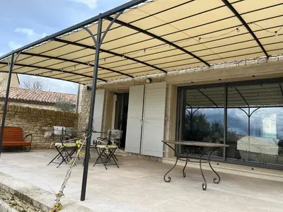 a pergola over a patio with a table and chairs at Maison dans un hameau avec piscine in Gordes