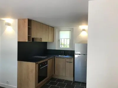 a kitchen with wooden cabinets and a stainless steel refrigerator at Le clos de la Touloubre in Aix-en-Provence