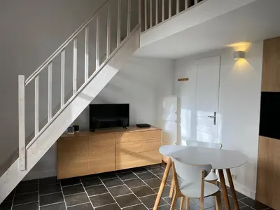 a living room with a table and a tv and stairs at Le clos de la Touloubre in Aix-en-Provence