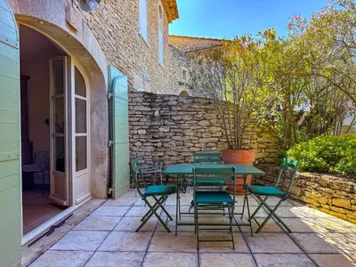 a green table and chairs on a patio at Villa de vacances à Gordes avec piscine partagée, La Bastide de Léa in Gordes