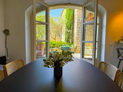 a dining room table with a vase of flowers on it at Villa de vacances à Gordes avec piscine partagée, La Bastide de Léa in Gordes