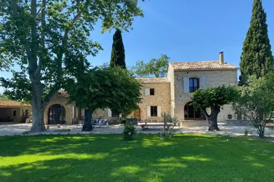 a large building with trees in front of a yard at The Farmhouse in the shade of the plane trees in Cavaillon