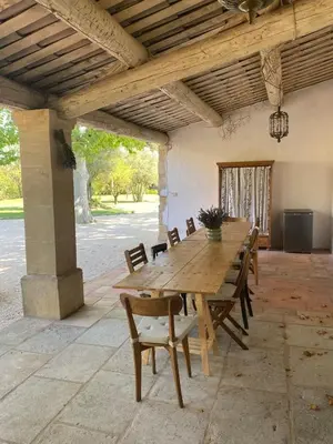 a wooden table and chairs on a patio at The Farmhouse in the shade of the plane trees in Cavaillon