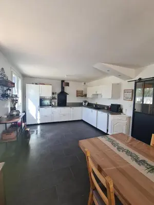 a large kitchen with white cabinets and a wooden table at Villa avec piscine en Provence in Pernes-les-Fontaines