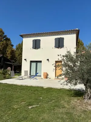a white house with black windows and a yard at La Petite Bastide en Provence in Noves