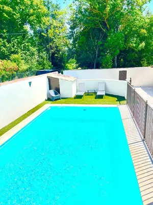 a swimming pool with blue water in a backyard at Le Cabanon Meublé de Tourisme trois étoiles in Entraigues-sur-la-Sorgue