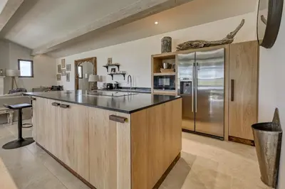 a kitchen with wooden cabinets and a stainless steel refrigerator at Villa Les Escapades d'Adrien, piscine, climatisation in Sannes