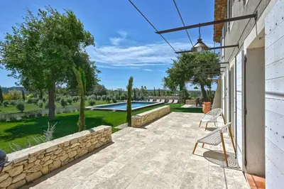 a patio with a stone wall and a chair at Villa Les Escapades d'Adrien, piscine, climatisation in Sannes
