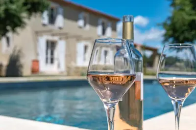 two glasses of white wine next to a swimming pool at Villa Les Escapades d'Adrien, piscine, climatisation in Sannes