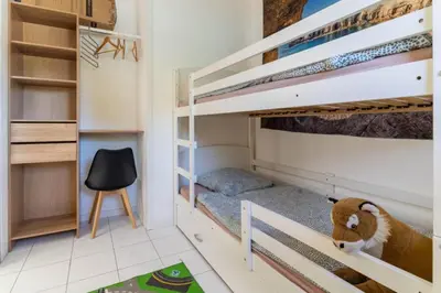 a childs bedroom with bunk beds and a chair at Le logis de la castagne in Caumont-sur-Durance