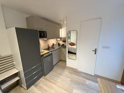 a small kitchen with white cabinets and a refrigerator at Studio terrasse in Aix-en-Provence
