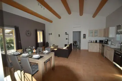 a kitchen and a living room with a table and chairs at les lauriers in Caromb