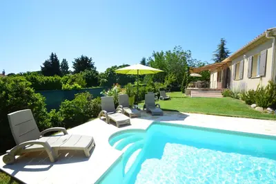 a pool with chairs and an umbrella next to a house at les lauriers in Caromb