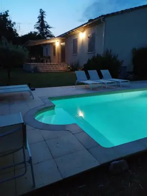 a swimming pool with chairs and a house at les lauriers in Caromb