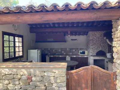 a kitchen with a stone wall and a refrigerator at Maison typique provençale au calme absolu dans le triangle d or a Bonnieux in Bonnieux