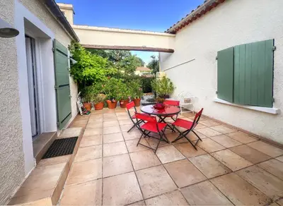 a patio with a table and chairs on a courtyard at La maison de l'olivier in Saint-Saturnin-les-Apt