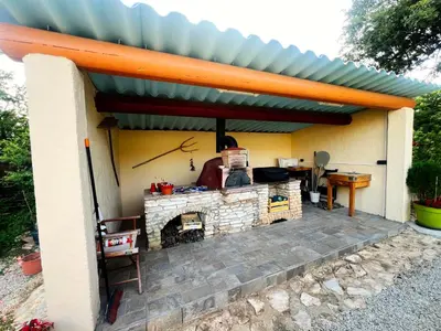 a patio with a roof over a stone fireplace at La maison de l'olivier in Saint-Saturnin-les-Apt