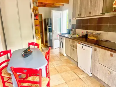 a kitchen with a table and red chairs in it at La maison de l'olivier in Saint-Saturnin-les-Apt