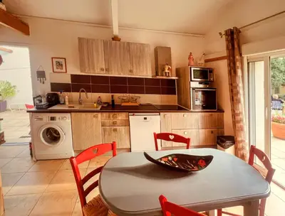 a kitchen with a table and chairs and a table and a sink at La maison de l'olivier in Saint-Saturnin-les-Apt