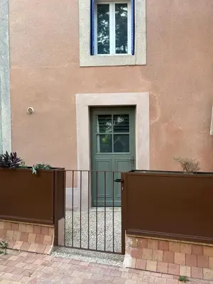 a house with a green door and a fence at Place ô sorgue ! in LʼIsle-sur-la-Sorgue