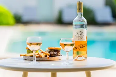 a bottle of wine and two glasses on a table at Villa & Piscine 8P entre Isle sur Sorgue et Avignon in Caumont-sur-Durance