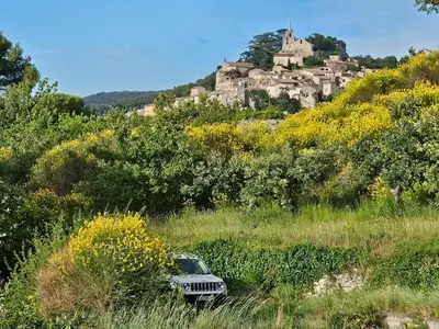 a jeep parked in a field in front of a castle at Vues imprenables, calme, nature, confort in Bonnieux
