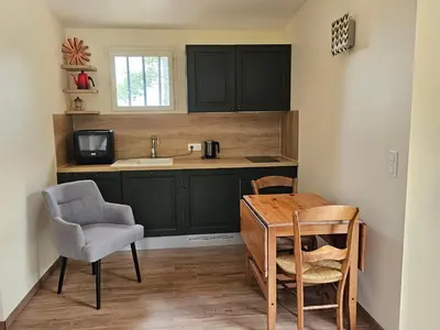 a kitchen with black cabinets and a table and a chair at Vues imprenables, calme, nature, confort in Bonnieux