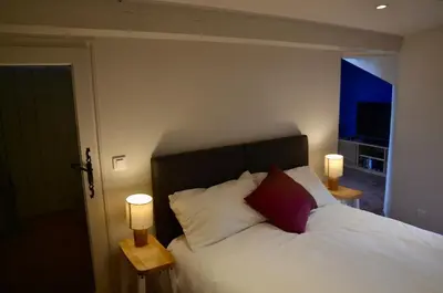 a bedroom with a white bed with two lamps at La Serre in Viens