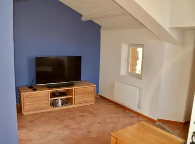 a living room with a flat screen tv on a wooden cabinet at La Serre in Viens